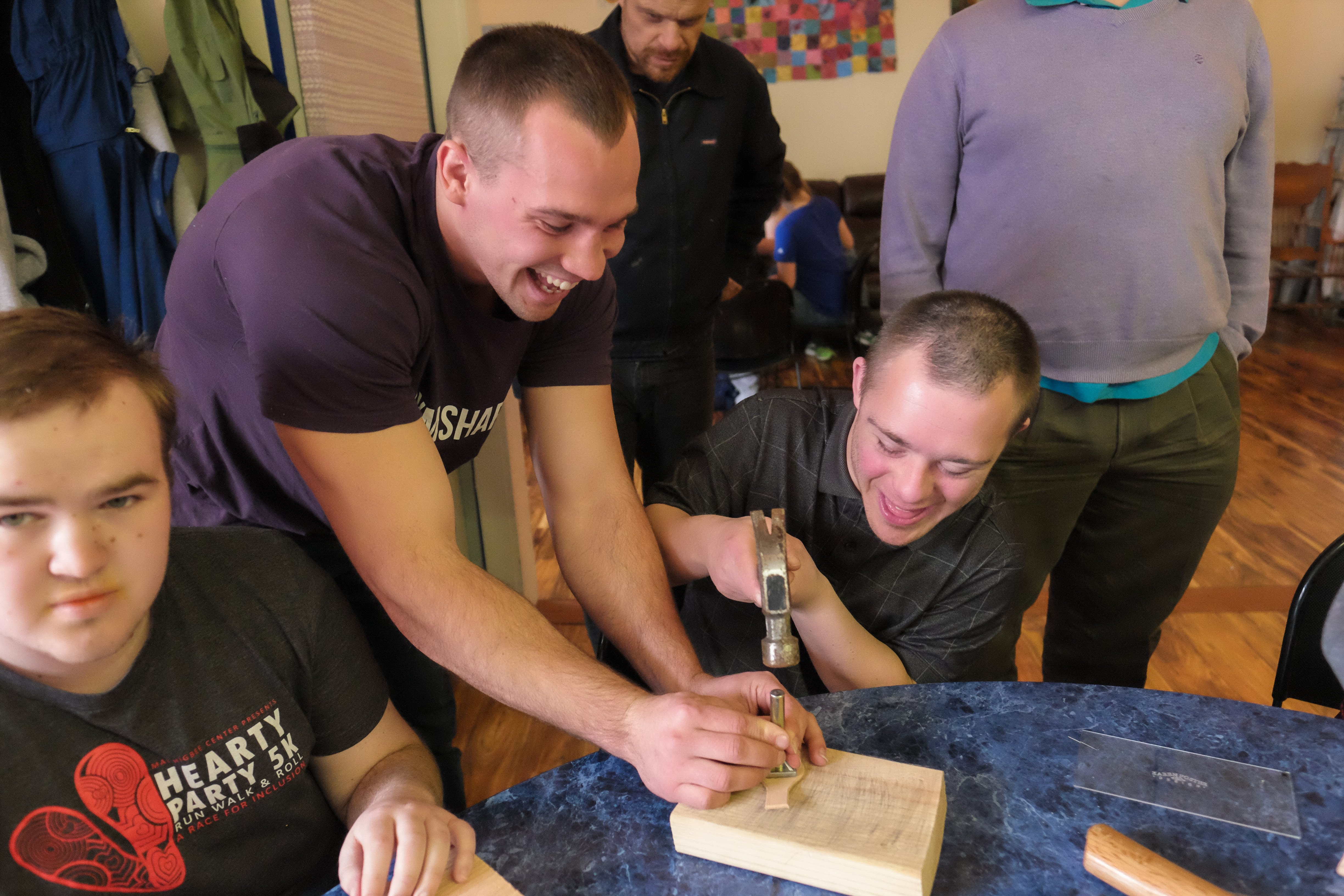 MHC members smile with volunteer while learning leather stamping